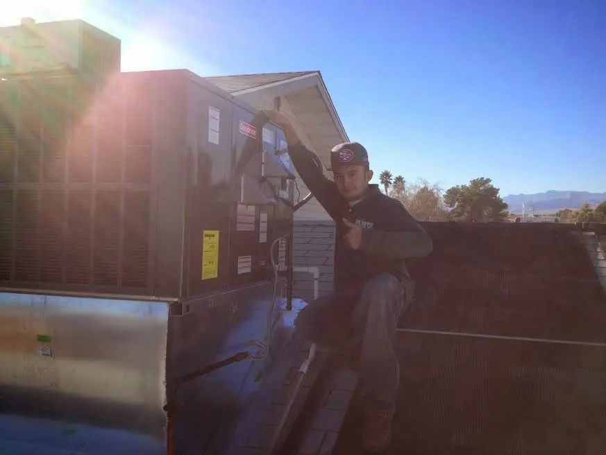 HVAC technician performing Air Duct Cleaning on a rooftop unit in Fredericksburg